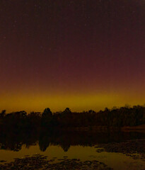 Aurora borealis lights over forest reflected in lake