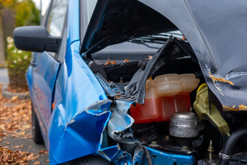 heavily damaged car with crumpled hood and exposed engine, aftermath collision, crash scene, with...