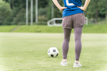 サッカー場でユニフォームを着てサッカー・フットサルの練習をする日本人女性
