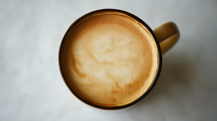 Top view of a creamy latte in a ceramic mug on a white surface.