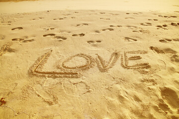 Word Love written on sand beach closeup brown background