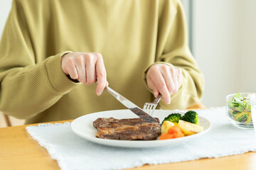 ステーキを食べるシニアの女性