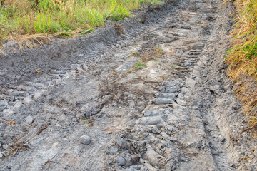 Dirt road with large tire marks running through it.