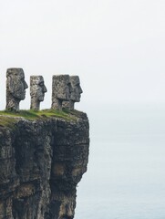 Three stone heads gaze out to sea from a cliffside perch. A serene, minimalist scene of contemplation and nature's grandeur.