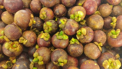 Close-up of a bunch of fresh mangosteens, showing their bright purple skin and green caps. Close-Up of fresh mangosteen background texture material.is a display in supermarket