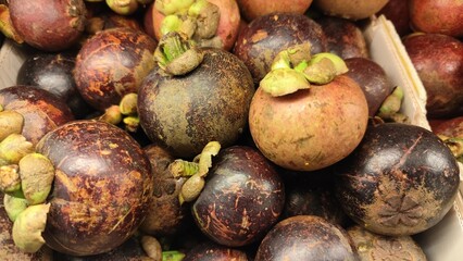 Close-up of a bunch of fresh mangosteens, showing their bright purple skin and green caps. Close-Up of fresh mangosteen background texture material.is a display in supermarket