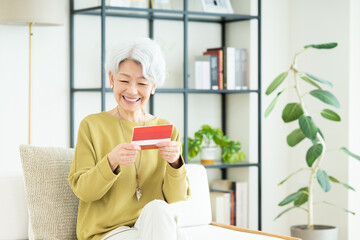 リビングで通帳を見るシニアの女性