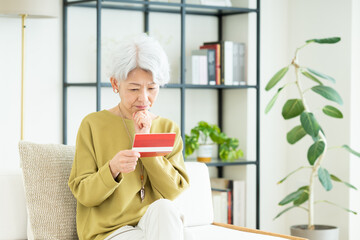 リビングで通帳を見るシニアの女性