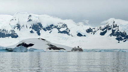 A cruise ship is dwarfed by mountains and ice fields in Antarctica.