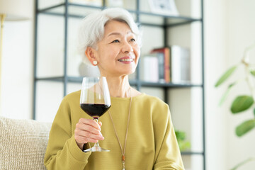 リビングで赤ワインを飲むシニアの女性