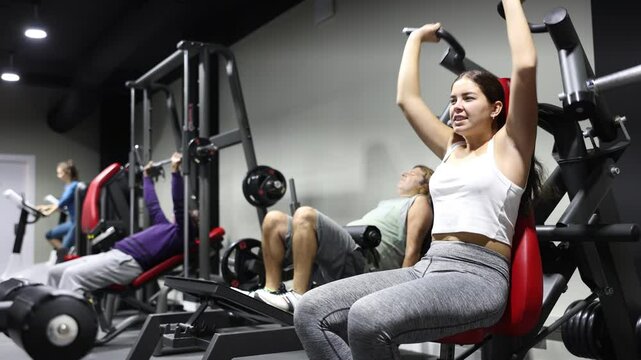 Caucasian woman doing exercises on shoulder press machine in gym