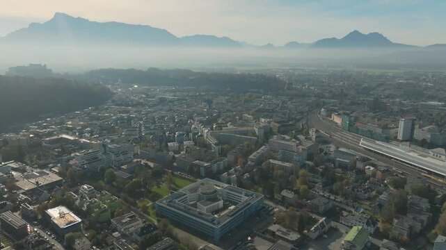 Salzburg Drone Aerial, Austria. Aerial View of Central Train Station and Cityscape and misty mountains