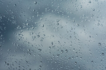 Rain drops are visible on a window glass, creating a textured pattern and a moody atmosphere.