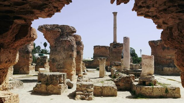 View of sun-drenched ruins of Roman Baths complex of Antoninus in ancient Phoenician town of Carthage with remnants of marble Corinthian columns and stone structures, Tunisia