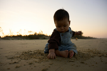 there is a baby sitting on the sand playing with a toy