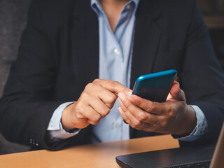 Close-up of a businessman holding a mobile phone, browsing or texting at work.