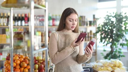 Young woman buyer scanning qr code for red smoothie in bottle in grocery store