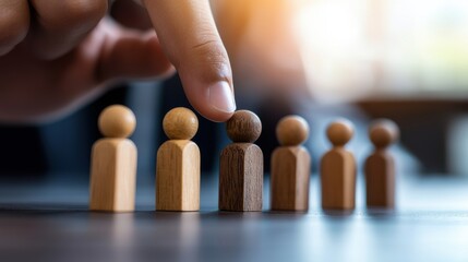 resource leadership human strategic HR concept. A hand points to a unique wooden figure among similar ones, symbolizing individuality and focus in a group setting.