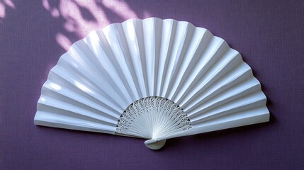 White folding fan on mauve background