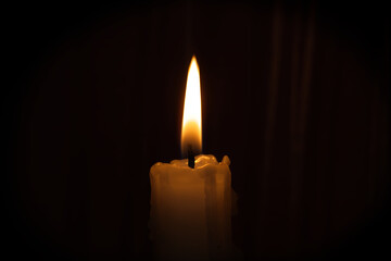 Single candle flame illuminates the darkness creating serene, comforting atmosphere with warm glow