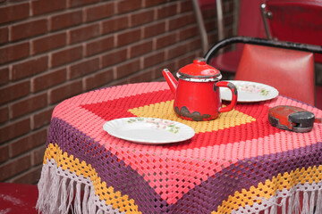 Colorful table setting with a red teapot and decorative cloth