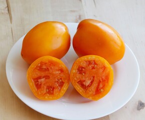Whole and sliced Orange Queen  tomatoes on a white plate