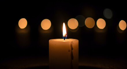 A single candle burns brightly in the darkness, creating a warm and serene ambiance with soft bokeh lights in the background