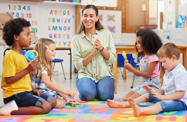 Teacher, kids and teaching music in classroom for creative learning, language development and support. Woman, children and instruments for singing game, sensory education and group activity at school