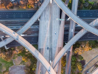 Aerial view of a complex highway interchange, showing cars traversing multiple levels. Urban landscape with residential areas and parkland below. Macarthur Freeway, Oakland, California, USA