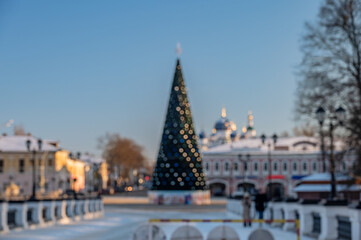 Fototapeta premium Blurred cityscape. Christmas background with New Year tree on city square.