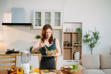 Smiling woman in a modern kitchen with fresh fruits, veggies, blender, and juice, embracing clean eating,