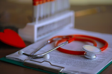 Doctor`s desk in the clinic's office. Stethoscope, test tubes, laptop, prescriptions on the table.
