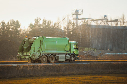 Green trash truck during sunrise commute
