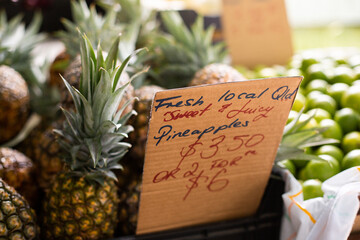 pineapples and limes for sale at the markets with a cardboard sign
