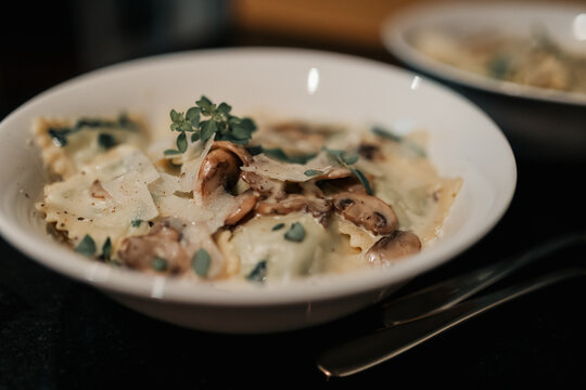 Tortellini pasta dish with creamy white sauce garnished with fresh oregano leaves
