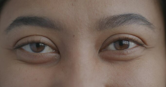 Close-up slow motion portrait of biracial woman's eyes looking at camera with no emotion. Face expression and human body part concept.