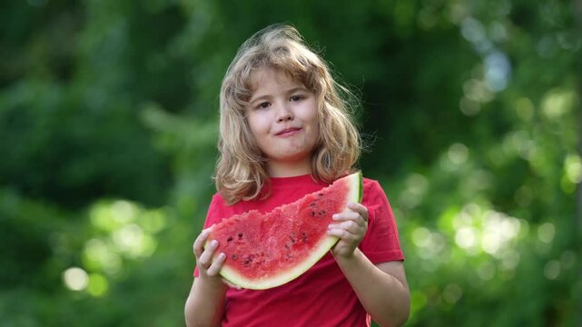 Happy kid eating a juicy watermelon in summer. A happy child biting into a slice of watermelon. A close-up portrait of a kid enjoying watermelon. Summer portrait of a child eating watermelon outdoors.