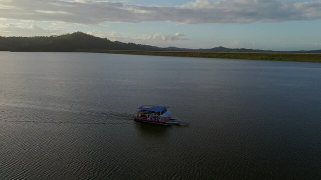 Ferry sailing on Hatillo Dam reservoir at sunset, Dominican Republic. Aerial drone orbiting, copy space