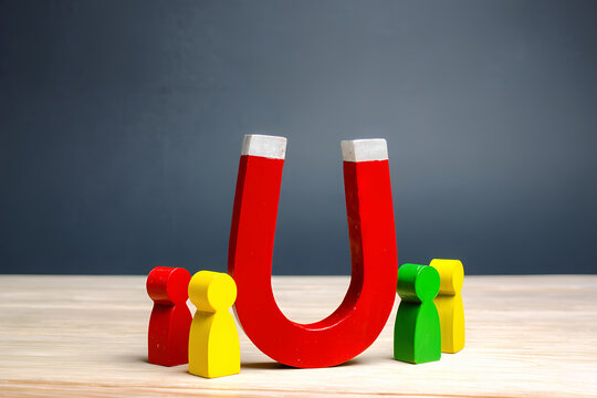 Colorful figurines of people surround red horseshoe magnet. Attracting clients core business strategy. Image represents customer acquisition. Retention strategies. Attracting new customers. Effective