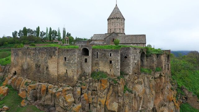 4K aerial drone footage of Tatev Monastery in Syunik (Zangezur) province, Armenia, during spring. The historic medieval monastery is surrounded by lush green mountains and the stunning Vorotan Canyon