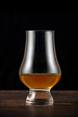 Close-up of single malt whiskey or scotch whisky tasting glass on dark wooden table