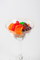 Fruit flavored worm shape, jelly candies in a glass on white background. 