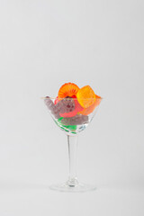 Fruit flavored worm shape, jelly candies in a glass on white background. 
