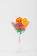 Fruit flavored worm shape, jelly candies in a glass on white background. 