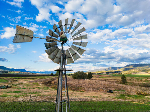 A metal windmill above a field and hilly area in south east Queensland