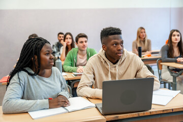 University students learning in classroom using laptop and notebook