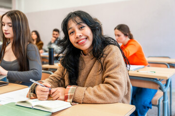 University student smiling and taking notes in classroom