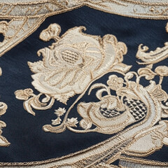 Fototapeta premium Floral embroidery on blue fabric. Close-up shot, gold stitching, decorative pattern, detailed textile backdrop