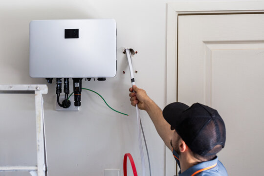 Electrician running wires and cables through wall for solar system install in residential home