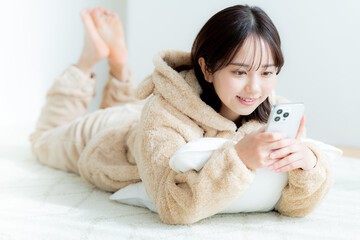 部屋でスマホを操作する若い女性